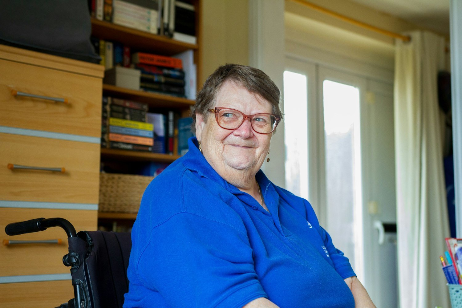 An older woman in a wheelchair smiling at home