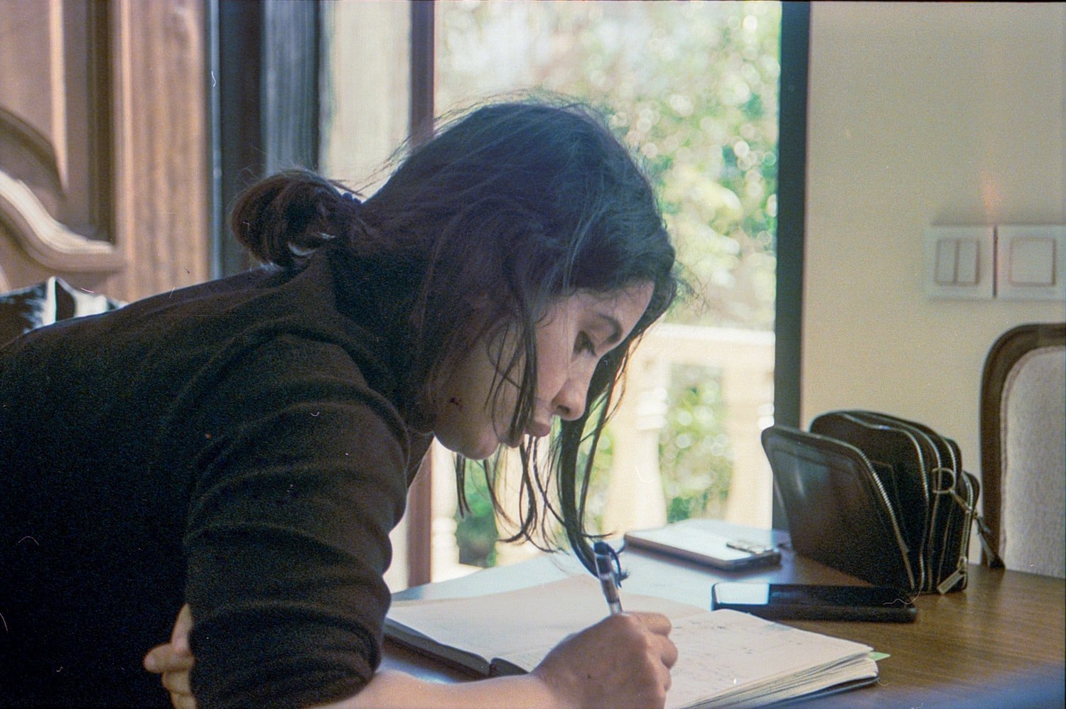 A woman writing in a notebook at a table while studying