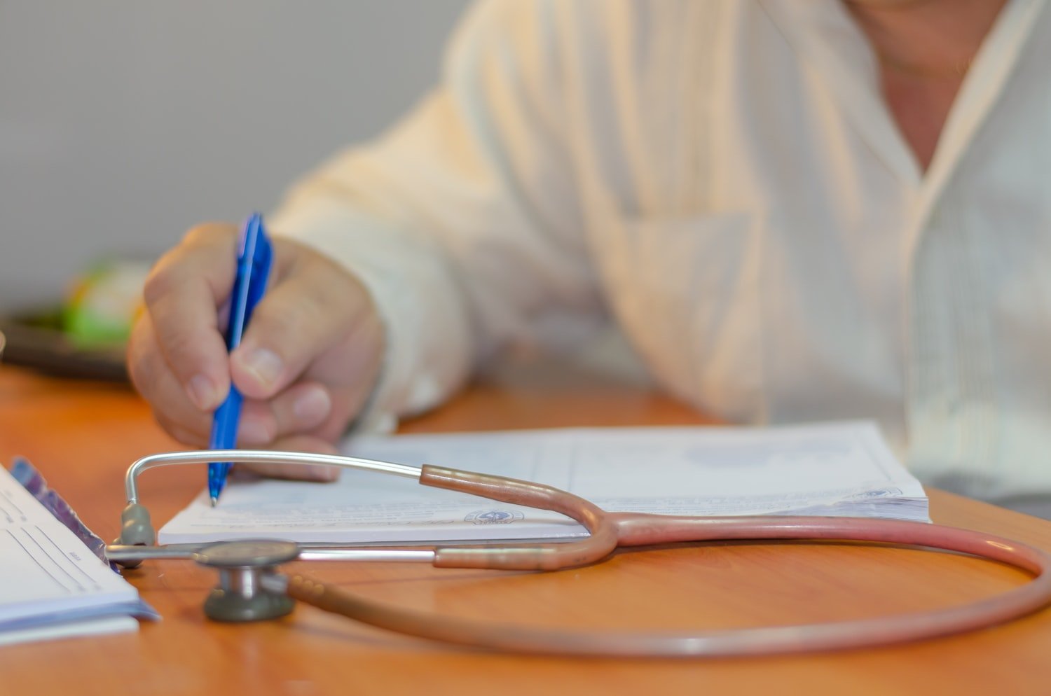 A person writing on paper beside a stethoscope, as when a clinician drafts a nexus opinion