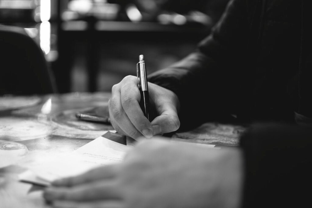 A person writing a letter on paper at a desk