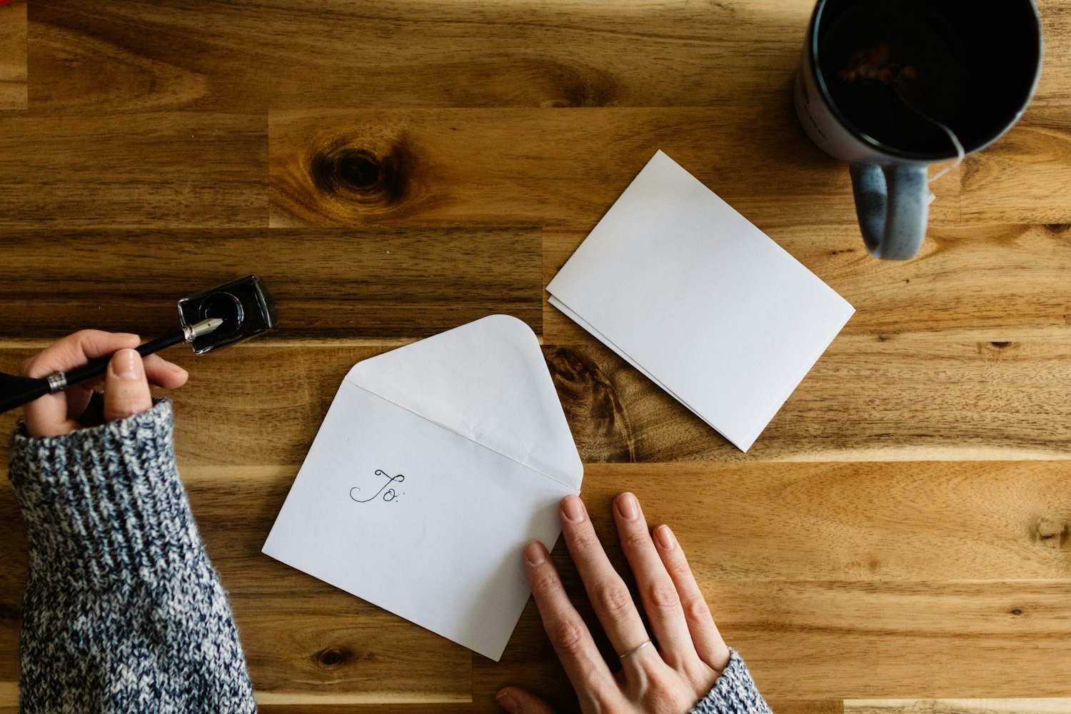 A person writing on paperwork beside a cup of coffee, as when completing a benefits application